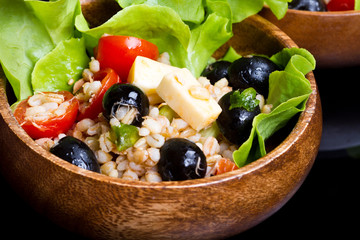 wood bowl with spelt salad with olives and tomatoes