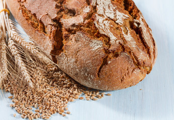 Fresh bread with wheat on the wooden background