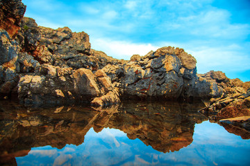 rocks and their reflection in the sea at daytime