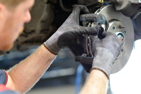 KFZ Mechaniker repariert Bremsen am Auto