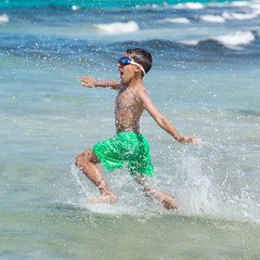 little boy running through the water on the beach