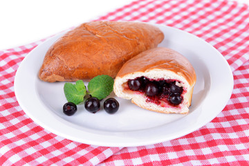 Fresh baked pasties with currant on plate on table close-up