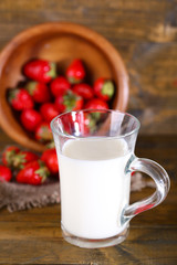 Ripe sweet strawberries in wooden bowl and glass with milk