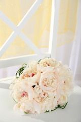 Beautiful wedding bouquet on chair on light background
