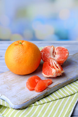 Ripe grapefruits on cutting board, on wooden background