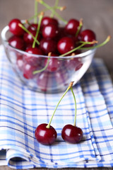 Cherries in color bowl on wooden background