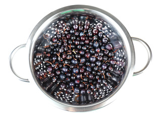 Black currants in colander isolated on white