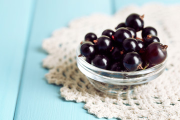Ripe blackcurrants in bowl on wooden background.