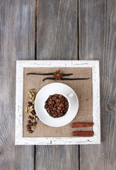 Wooden frame with white mug, coffee grains and spices