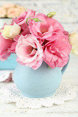 Bouquet of eustoma flowers in vase on wooden background