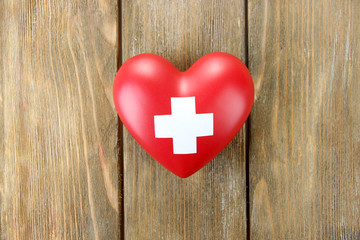 Red heart with cross sign on wooden background