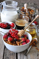 Healthy breakfast with granola, berries, milk, honey and coffee