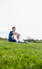 Fototapeta na wymiar Football player in blue taking a break on the pitch