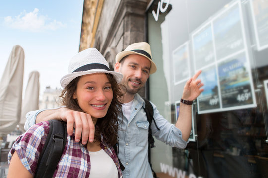 Young happy couple in front of travel agency