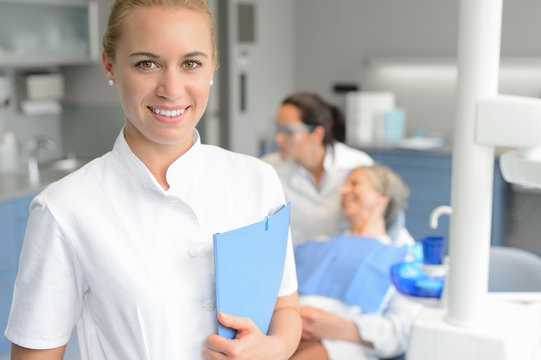 Dental assistant smiling dentist with patient