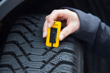 Frau misst Reifenprofil eines Autoreifen © Gina Sanders