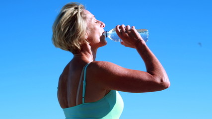 Fit senior woman pausing on her run to take a drink - Powered by Adobe