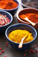 spices in bowls: curry, pink and black pepper, paprika powder