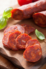 spanish chorizo sausage with basil on chopping board