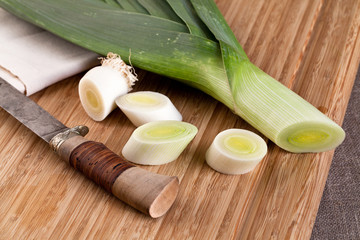 Fresh leeks whole and sliced on a wooden board