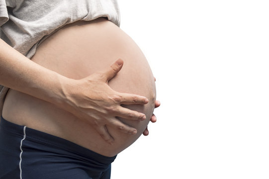 Close up of unrecognizable pregnant woman with hands over tummy.