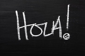 The Spanish word Hola written on a blackboard