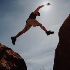 Fotobehang Man jumping between rocks © pixelLab