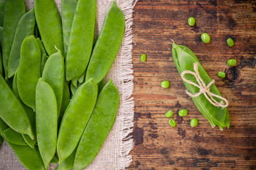 young pods of green peas on a wooden background