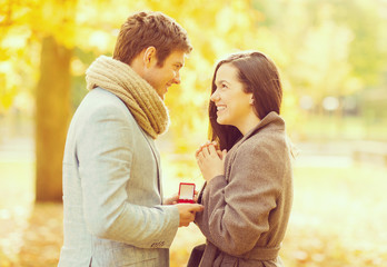 man proposing to a woman in the autumn park