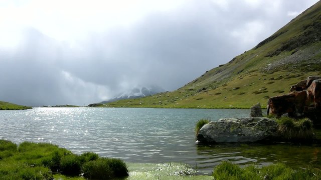 Silhouettes of lake banks in Alpine mountains, heavy dark clouds