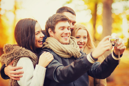 group of friends with photo camera in autumn park