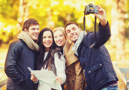 group of friends with photo camera in autumn park