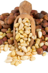 pine nuts in a wooden scoop isolated on white background