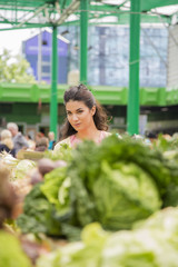 Pretty young woman buying vegetables on the market