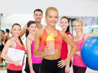 smiling sporty woman with protein shake bottle