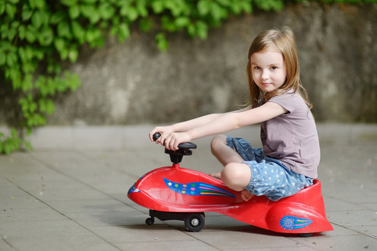 Adorable Little Girl Driving A Toy Car