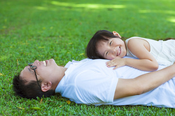 father and daughter lying on a meadow in the park