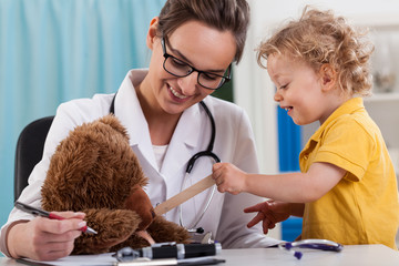 Doctor and little boy examining a teddy bear