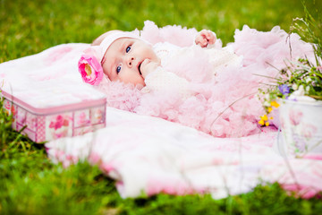 Fototapeta na wymiar cute newborn girl in pink skirt gnaws fingers