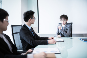 Young business people sitting in board room during meeting and d