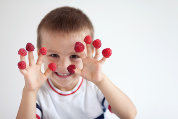 Adorable boy, having fun with raspberries