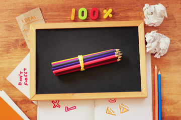 top view of blackboard , stack of pencils and crumpled paper.  