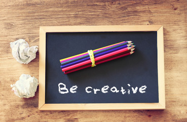 top view of crumpled paper and pencils stack over blackboard wit