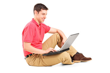 Young man working on laptop seated on the floor