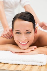 Obraz na płótnie Canvas Peaceful brunette enjoying a herbal compress massage smiling at