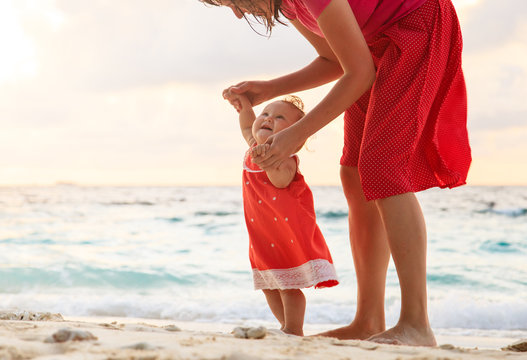 Mother And Daughter Walking On Sand Beach