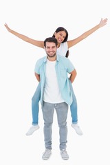 Happy casual man giving pretty girlfriend piggy back