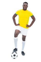 Football player in yellow standing with the ball