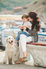 The happy mother and son sitting on the beach with the dog.