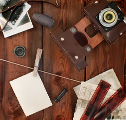 Retro camera, film and photos on old wooden background